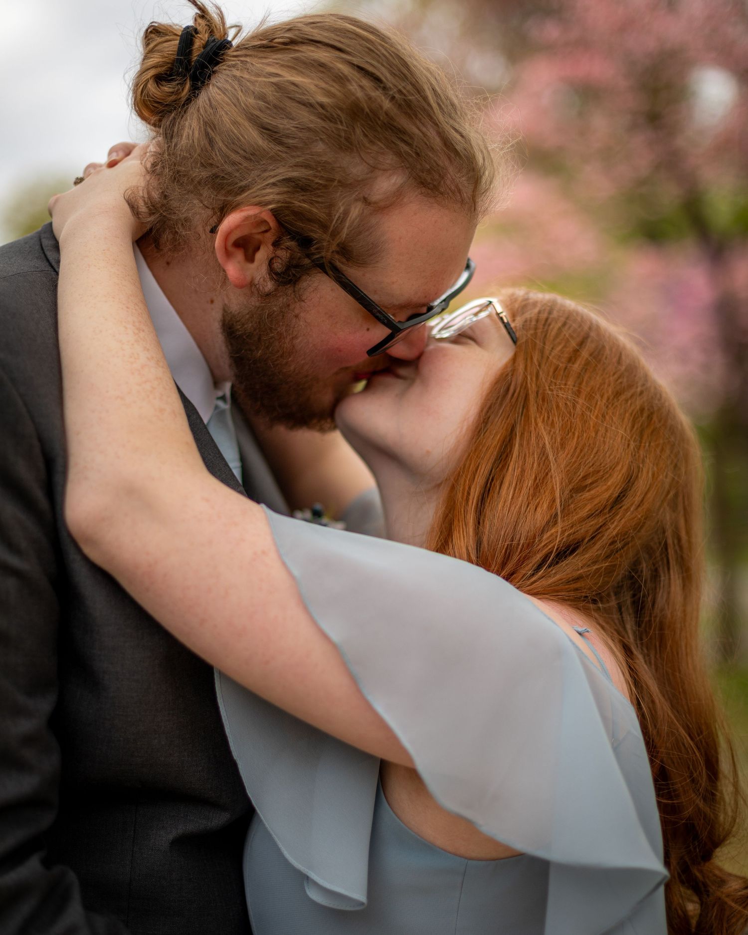Romantic kiss between couple under blooming cherry blossoms.
