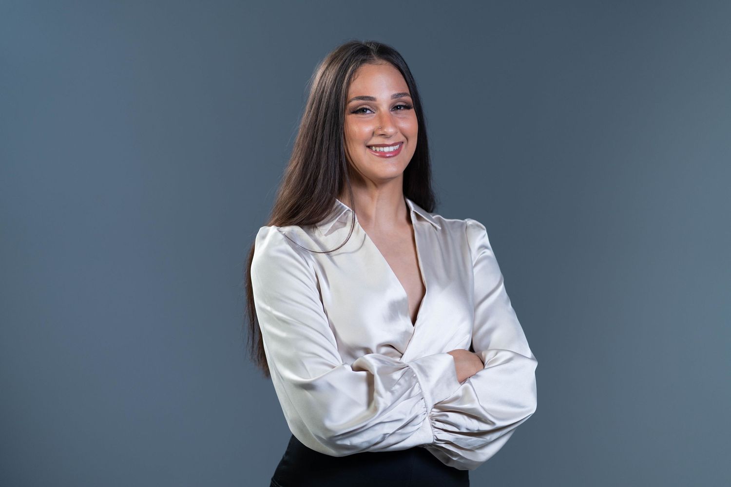 Polished woman in a satin blouse, radiating confidence and grace in a professional headshot.