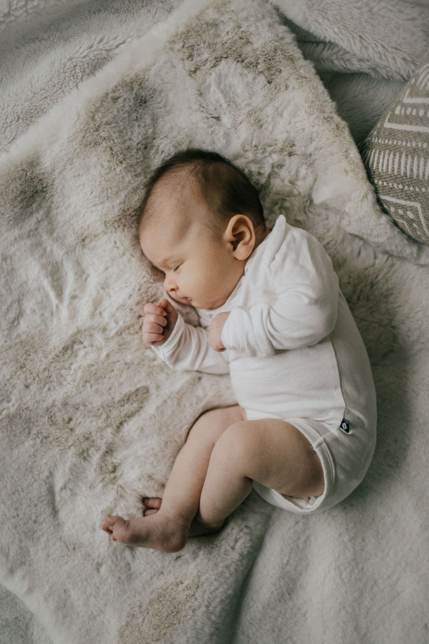 Image of a baby laying on white blankets fast asleep.