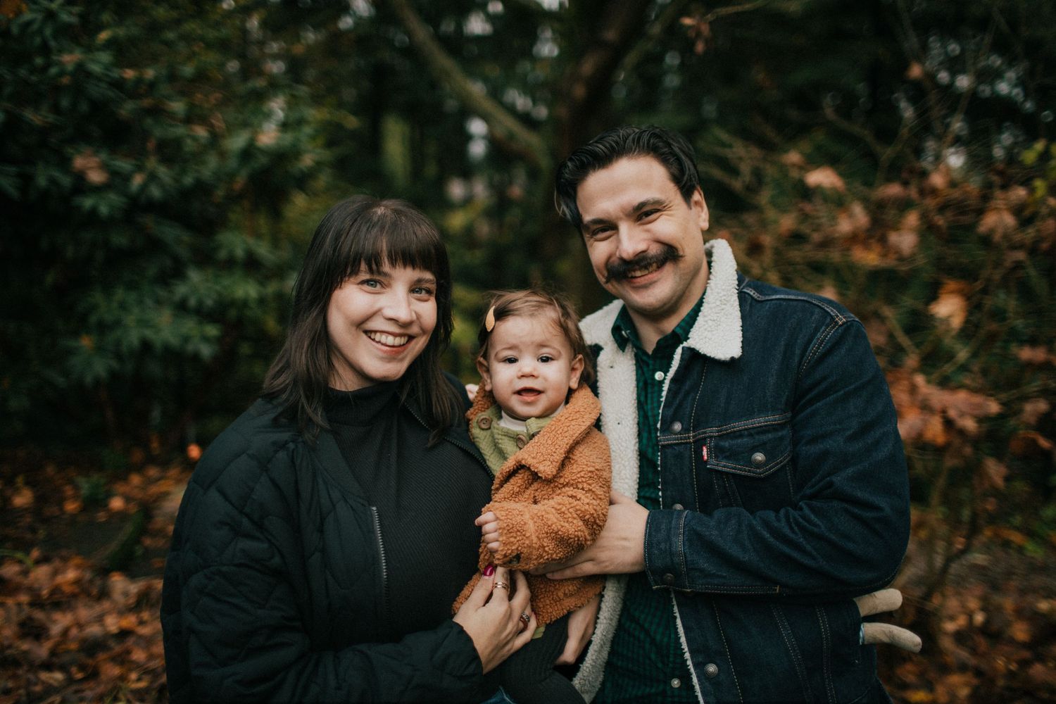 Image of a mom, dad, and little girl smiling at the camera.