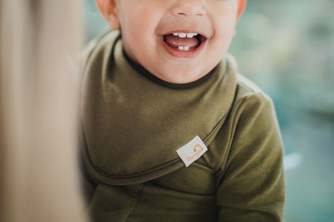 Close up image of a baby's chin showcasing a green bib and onesie.
