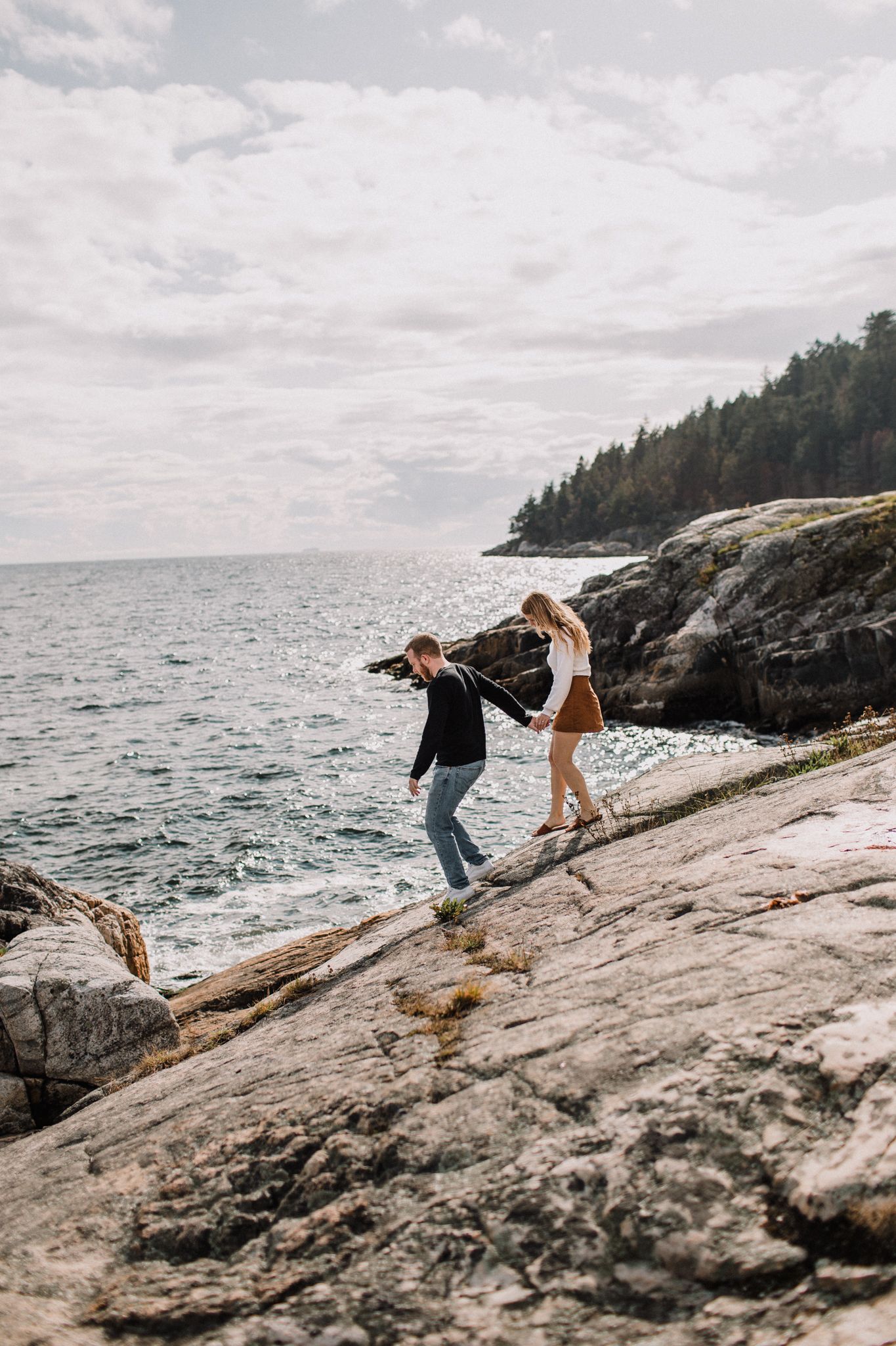 Image of a young couple walking on cliffs along the ocean.
