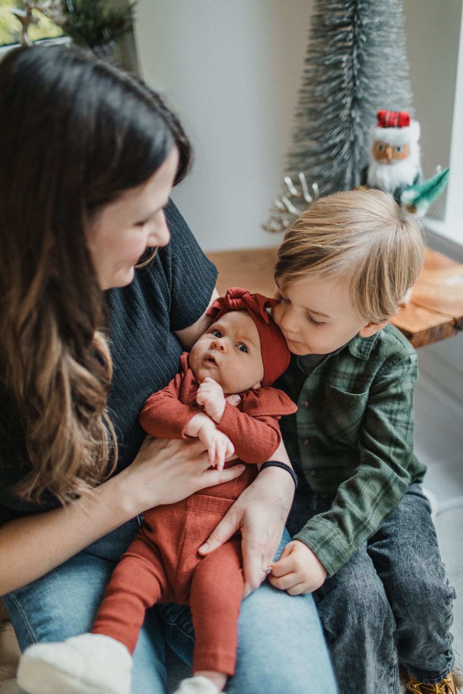 Image of a mom and three-year-old son looking at the new addition to the family: a baby girl.