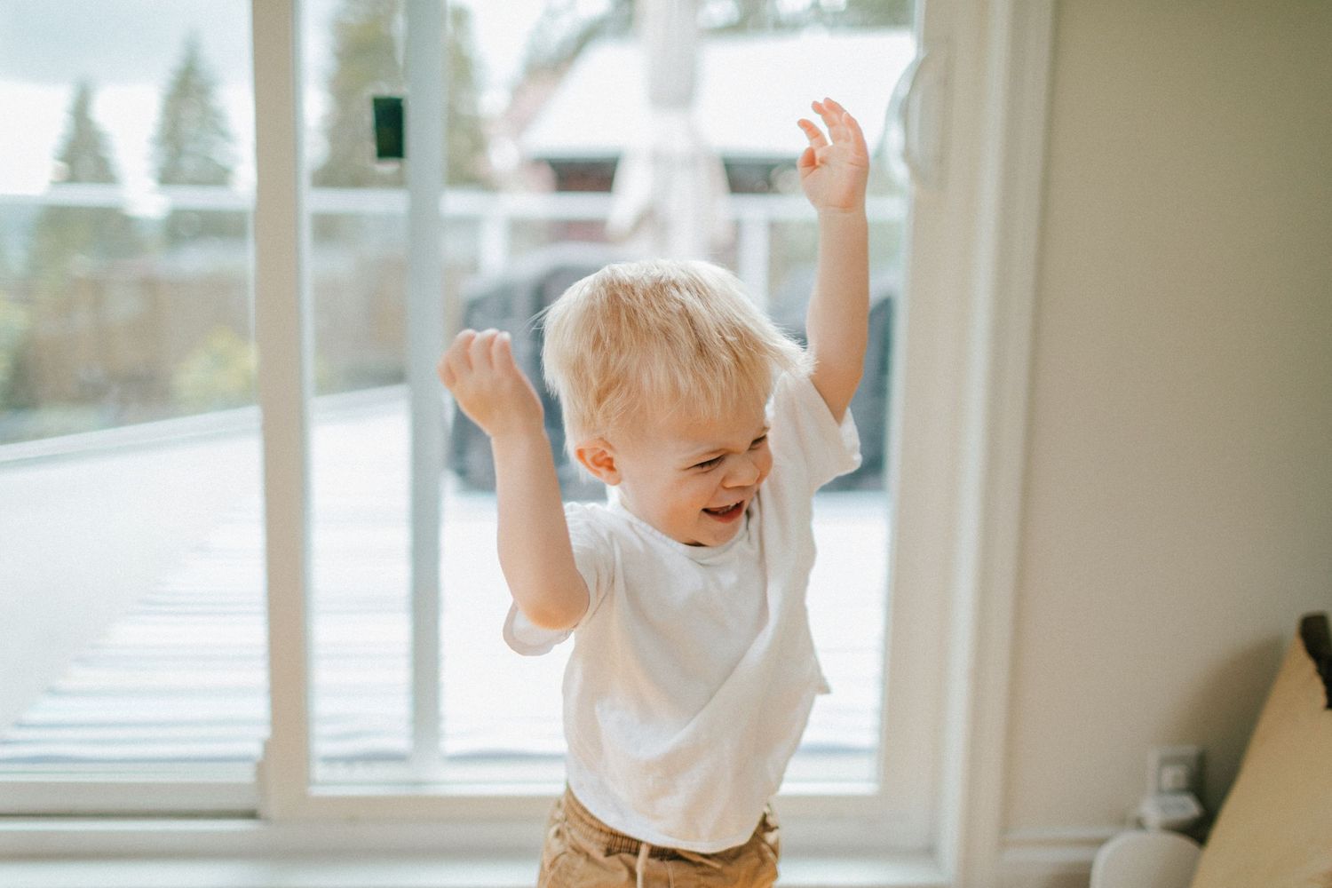 Image of a toddler laughing while throwing hands in the air.