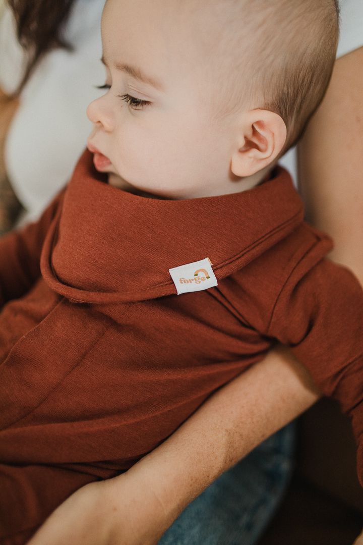 Image of a baby wearing red onsie and bib.