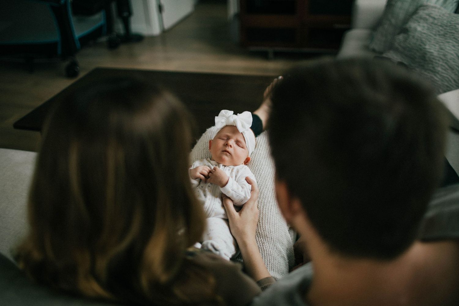 Image of two parents who are looking at their baby whose asleep on mom's lap.