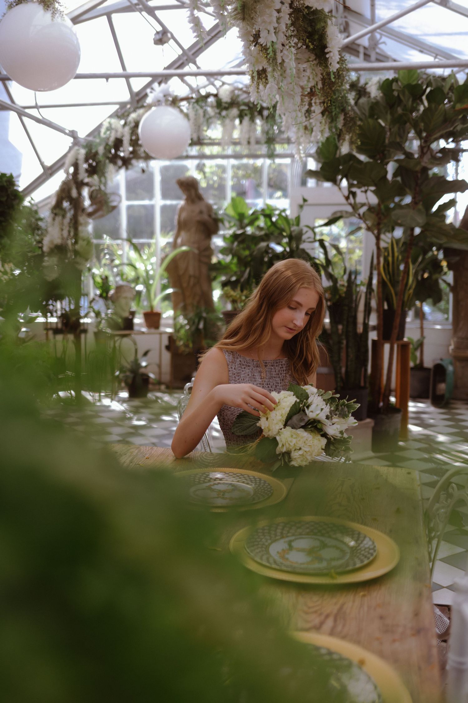 A romantic greenhouse dining setting with delicate floral arrangements and glowing lights creates an ethereal atmosphere.