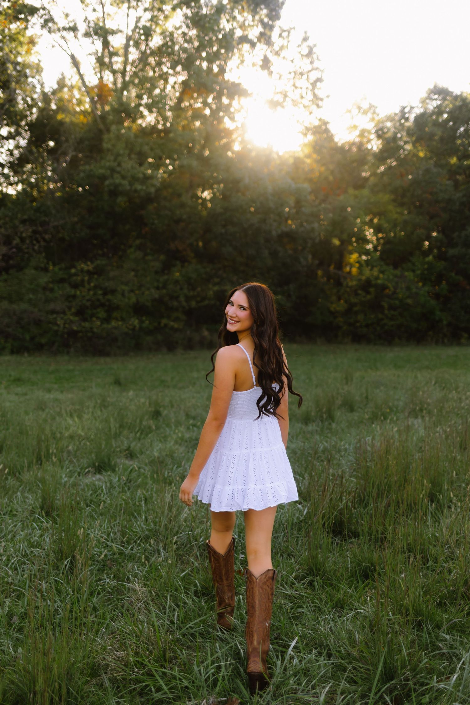 A person in a white sundress walks through a sunlit meadow at golden hour, creating a dreamy summer scene.