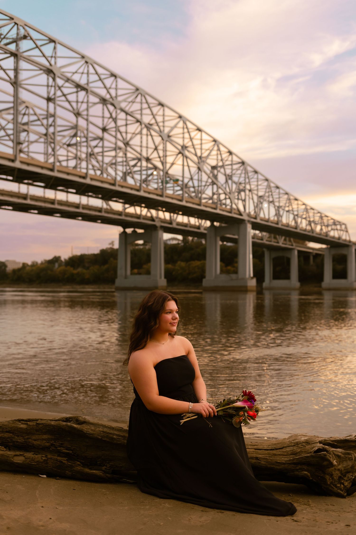 A series of photos shows someone in a black dress sitting by a river at sunset with a steel bridge in the background.