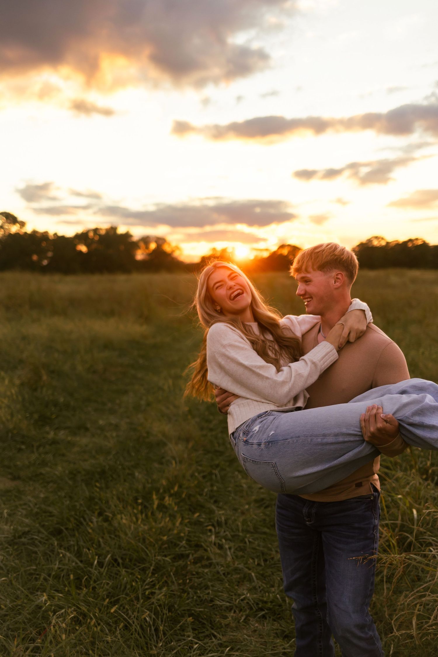 A joyful couple shares a playful moment in a golden field at sunset, creating a warm and romantic atmosphere.