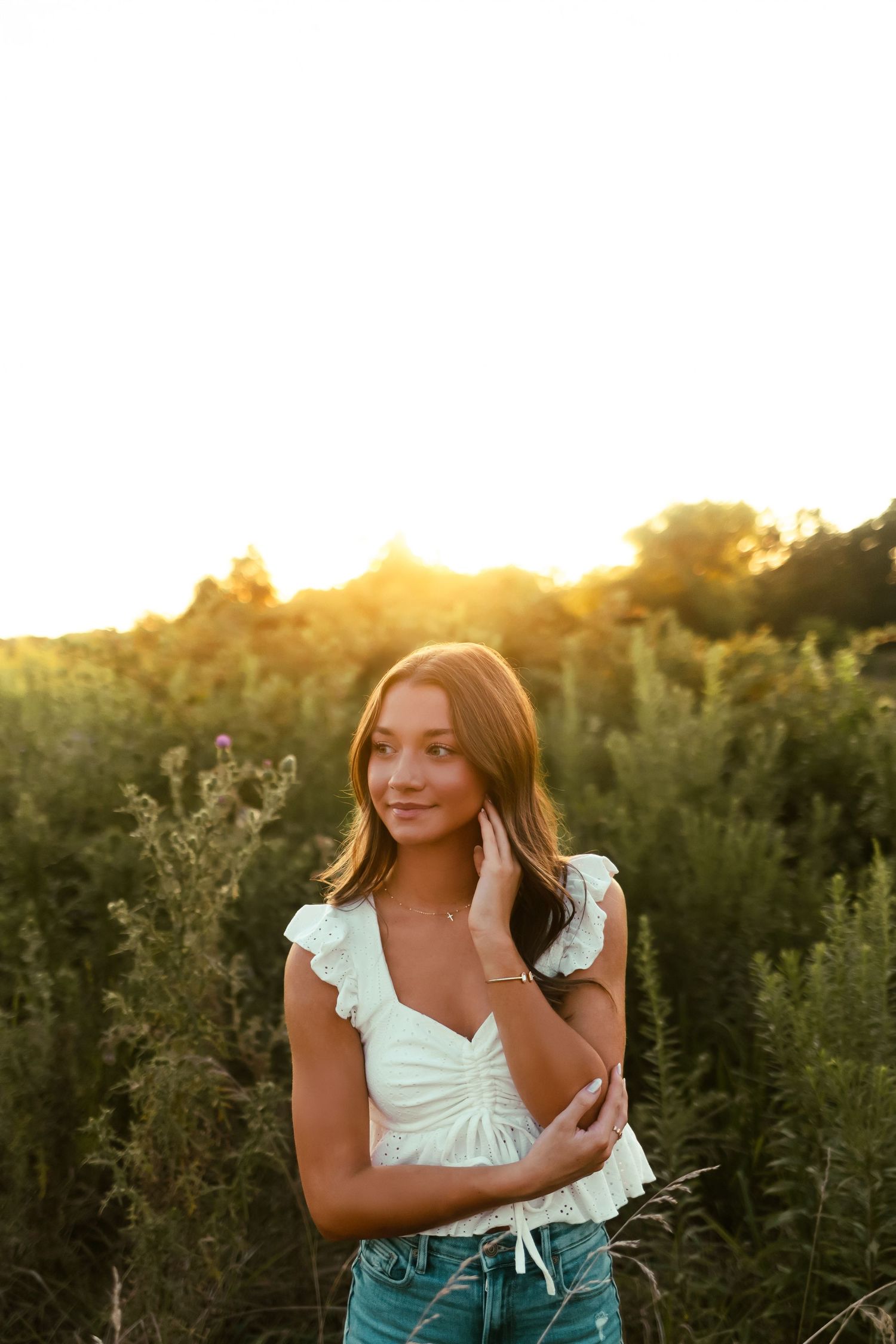 Golden sunset light illuminates a summer outdoor portrait session in a lush meadow field.