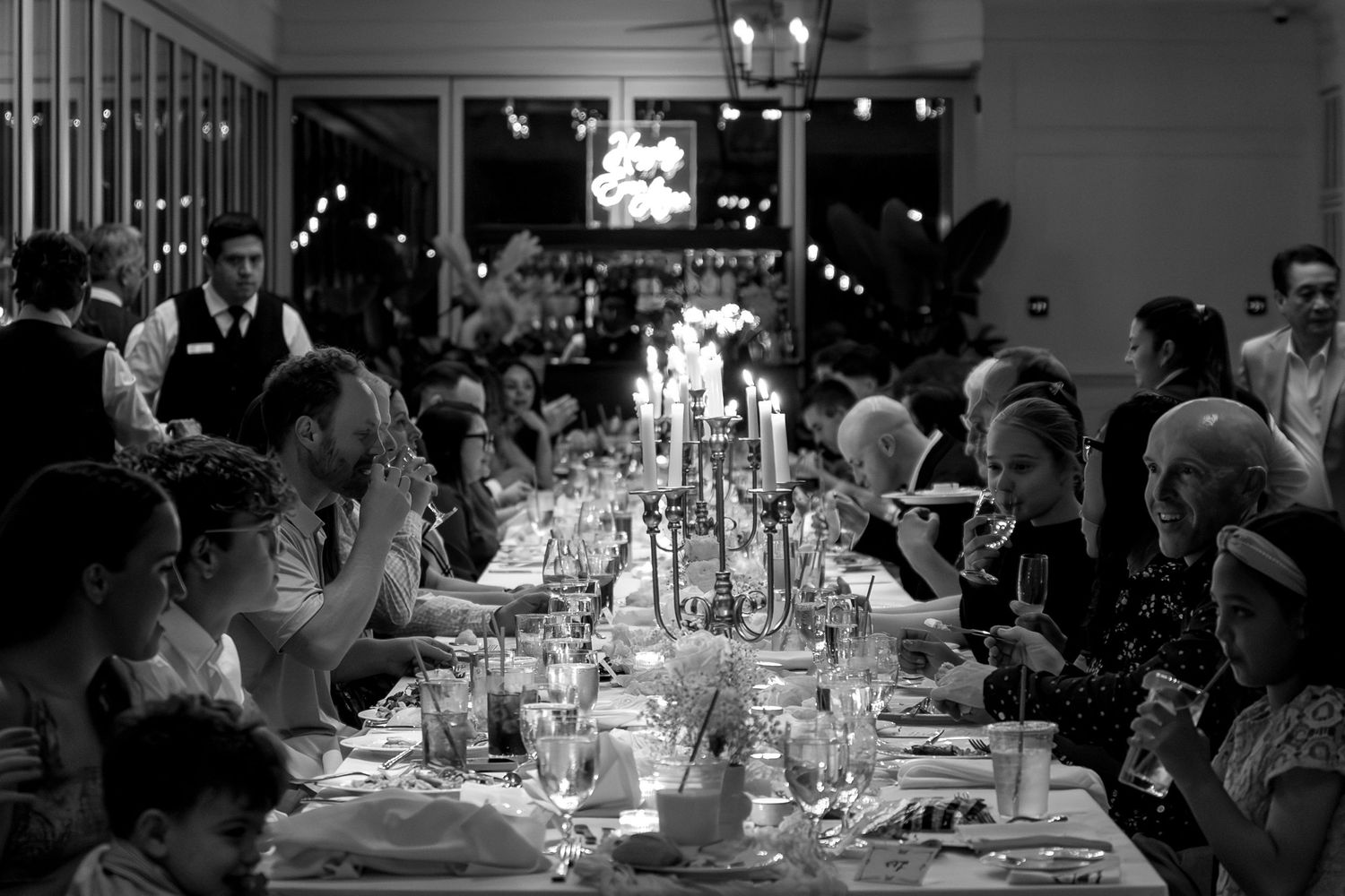 A panoramic view of an elegant wedding reception with candlelit tables and guests gathered in a dimly lit venue.