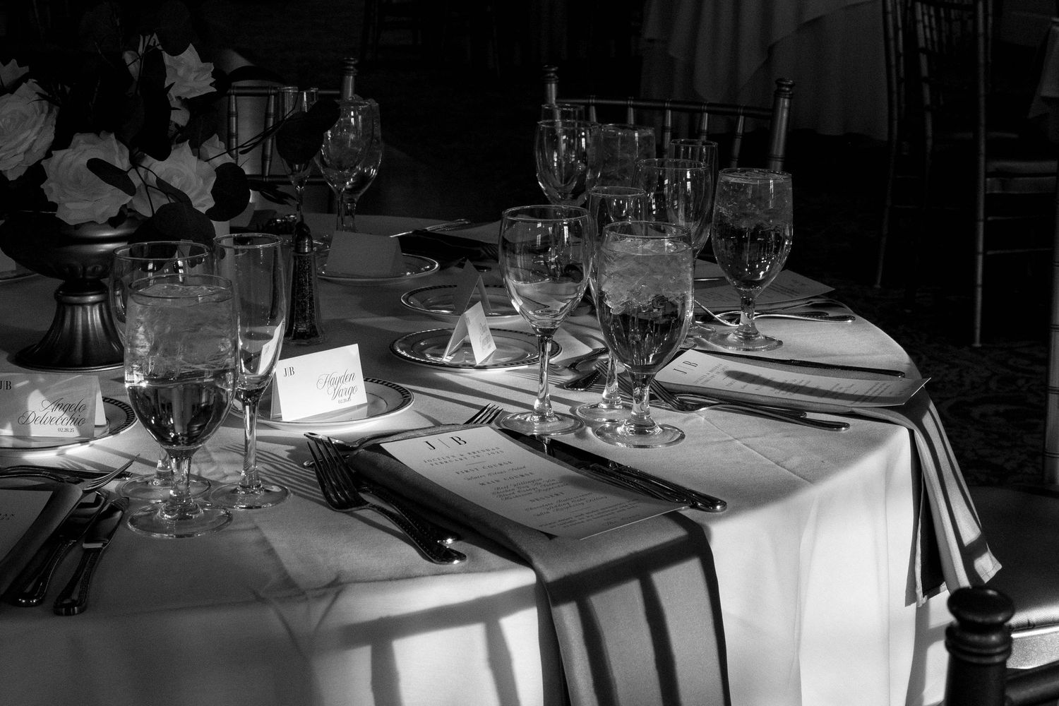 Elegant table settings with white linens and wine glasses in a dimly lit restaurant interior.