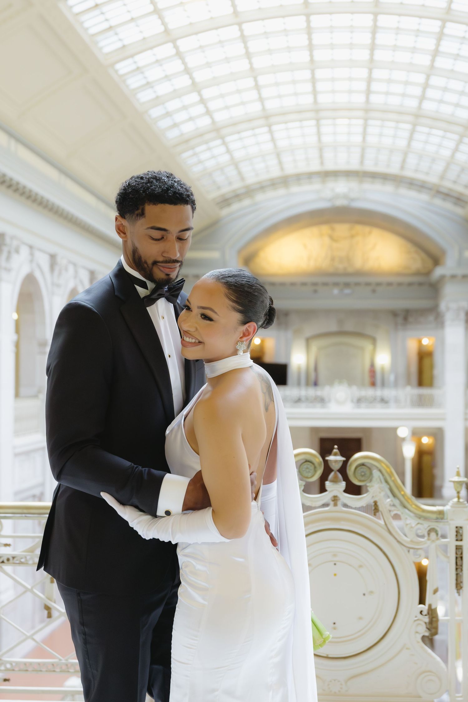 A romantic wedding photoshoot series showing tender moments between newlyweds in an elegant domed hall with ornate decor.