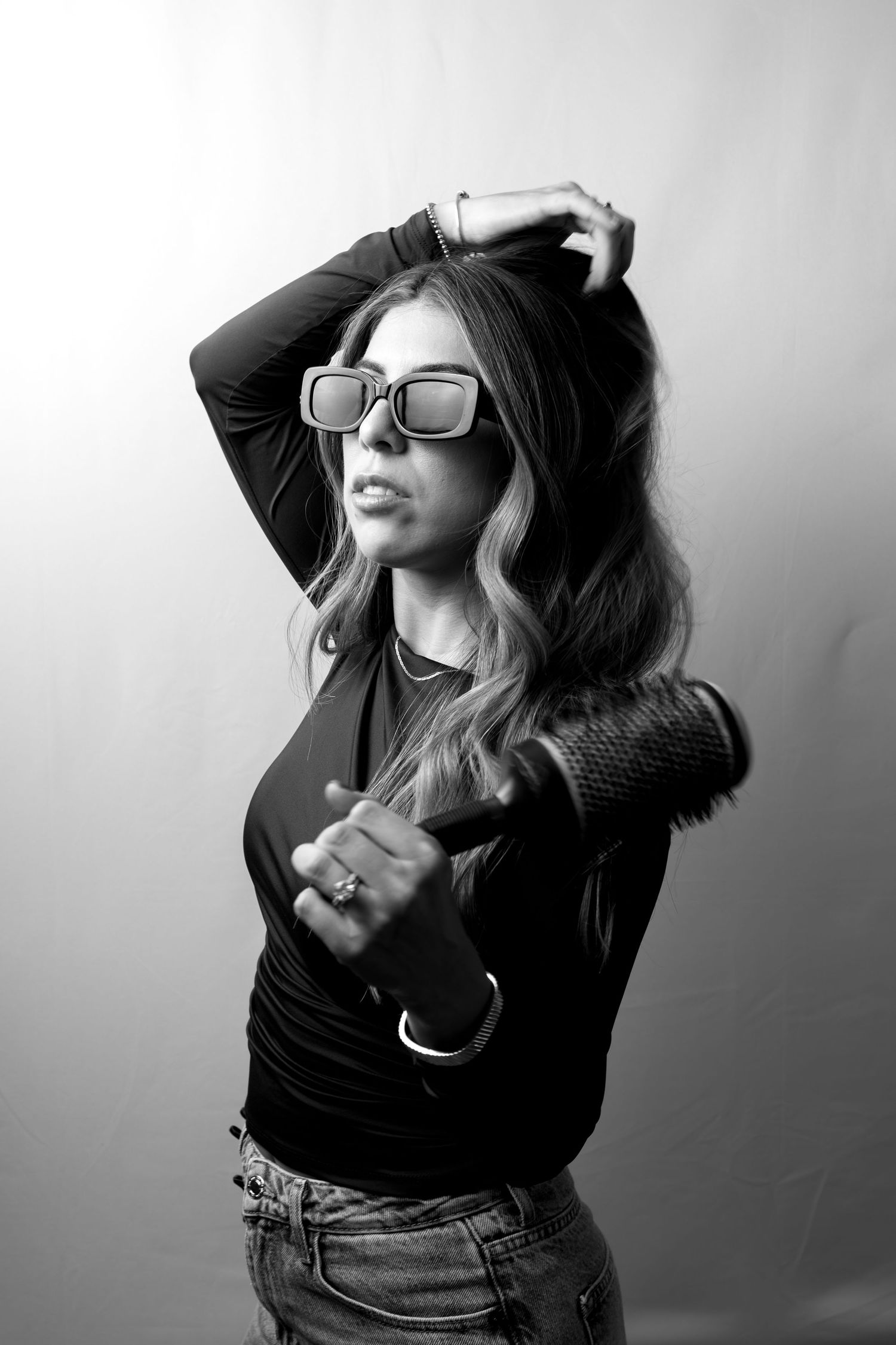 A black and white photo series showing someone with long hair and glasses posing dramatically against a wall.