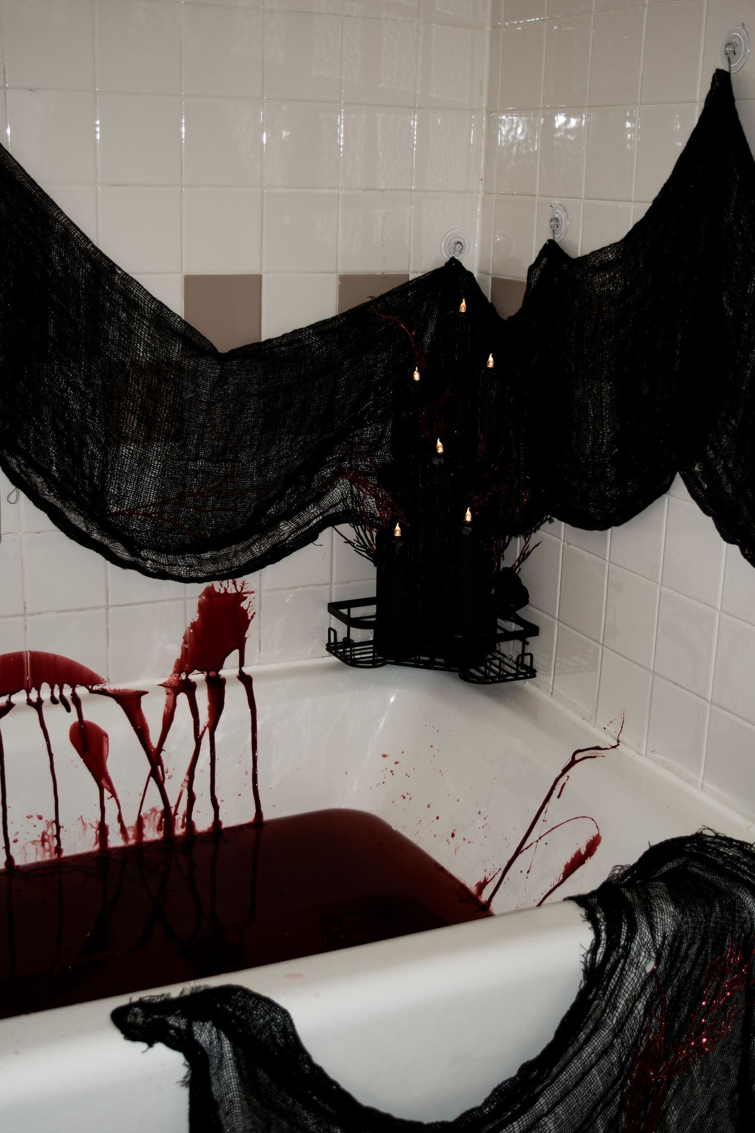 Black Halloween bats and red blood splatter decorations create a spooky scene on white bathroom walls.