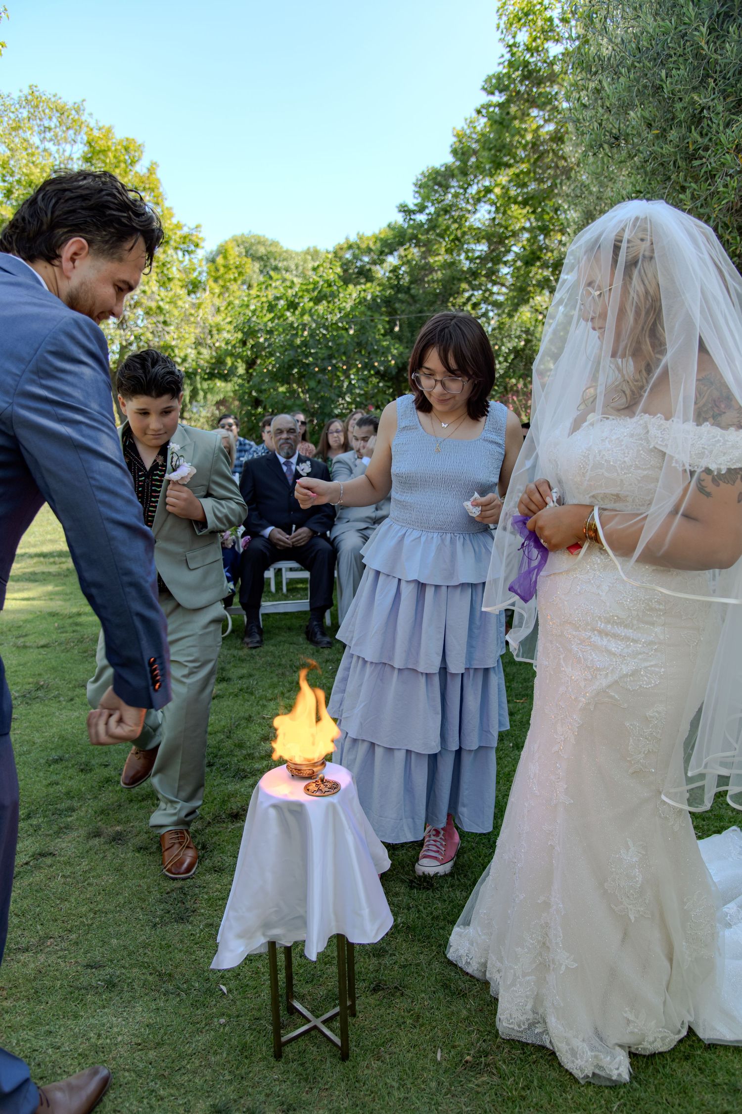 Wedding guests gather on a lawn during an outdoor ceremony with soft natural lighting.