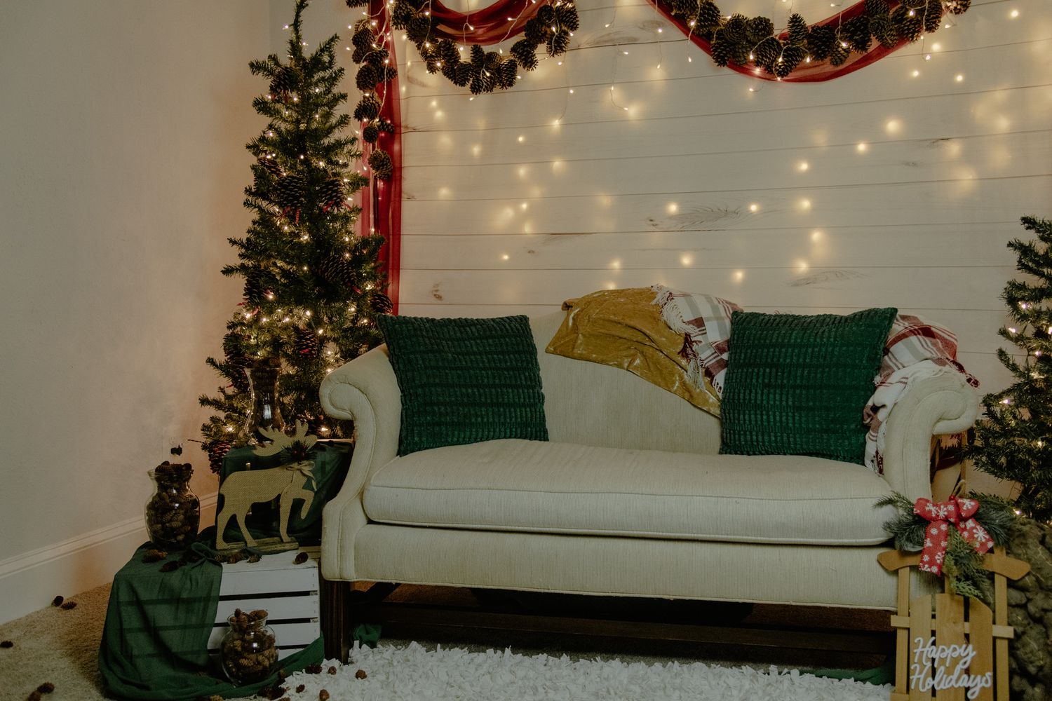 A cozy living room decorated for Christmas with a green couch, tree, and twinkling string lights on the wall.