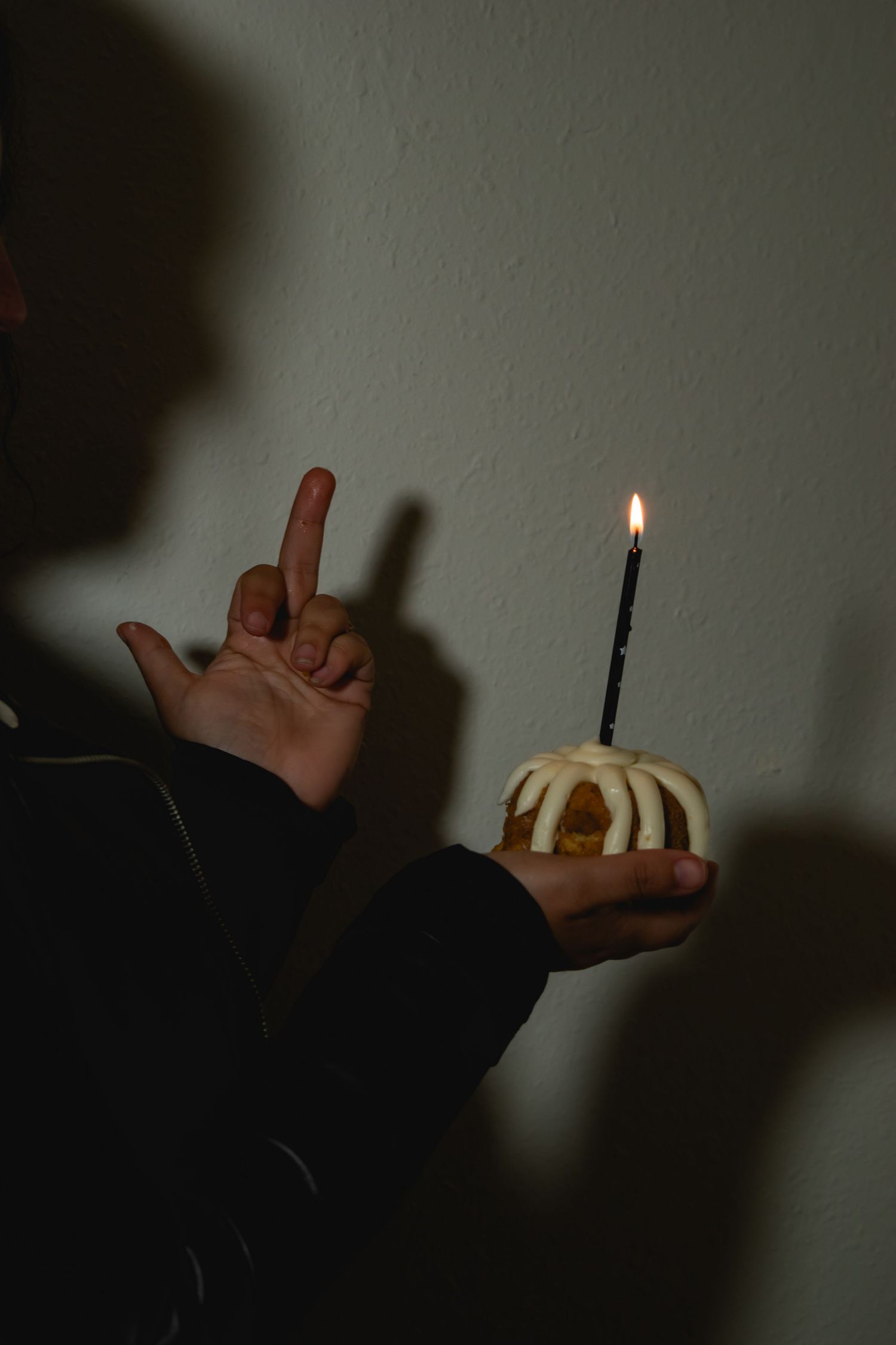 Hand holding multiple polaroid photos over dark surface with artistic shadows and moody lighting.