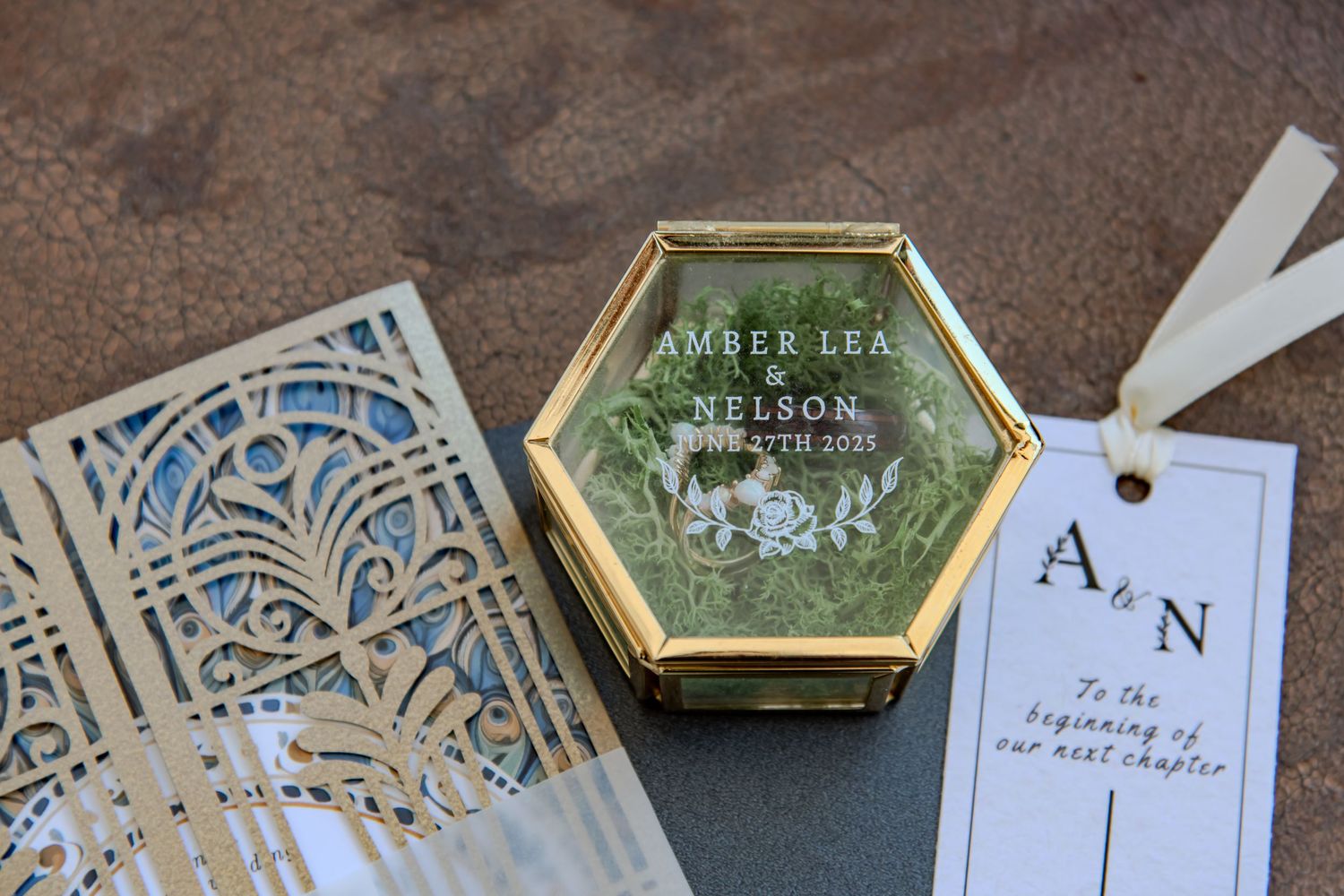 Elegant gold and glass wedding invitations with intricate floral designs and geometric patterns displayed together.