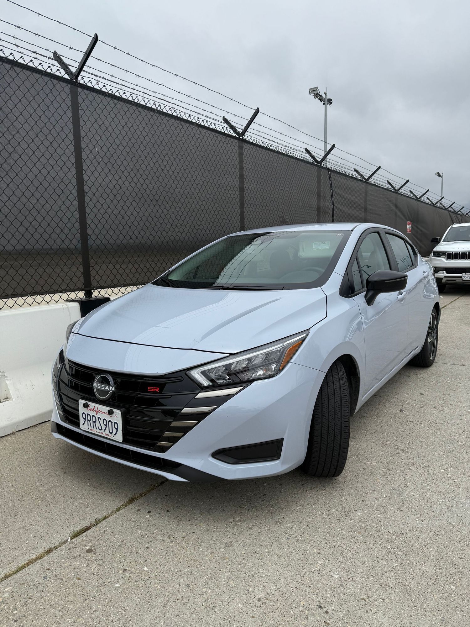 Side view of a Hyundai Sonata in silver parked against a chain link fence.