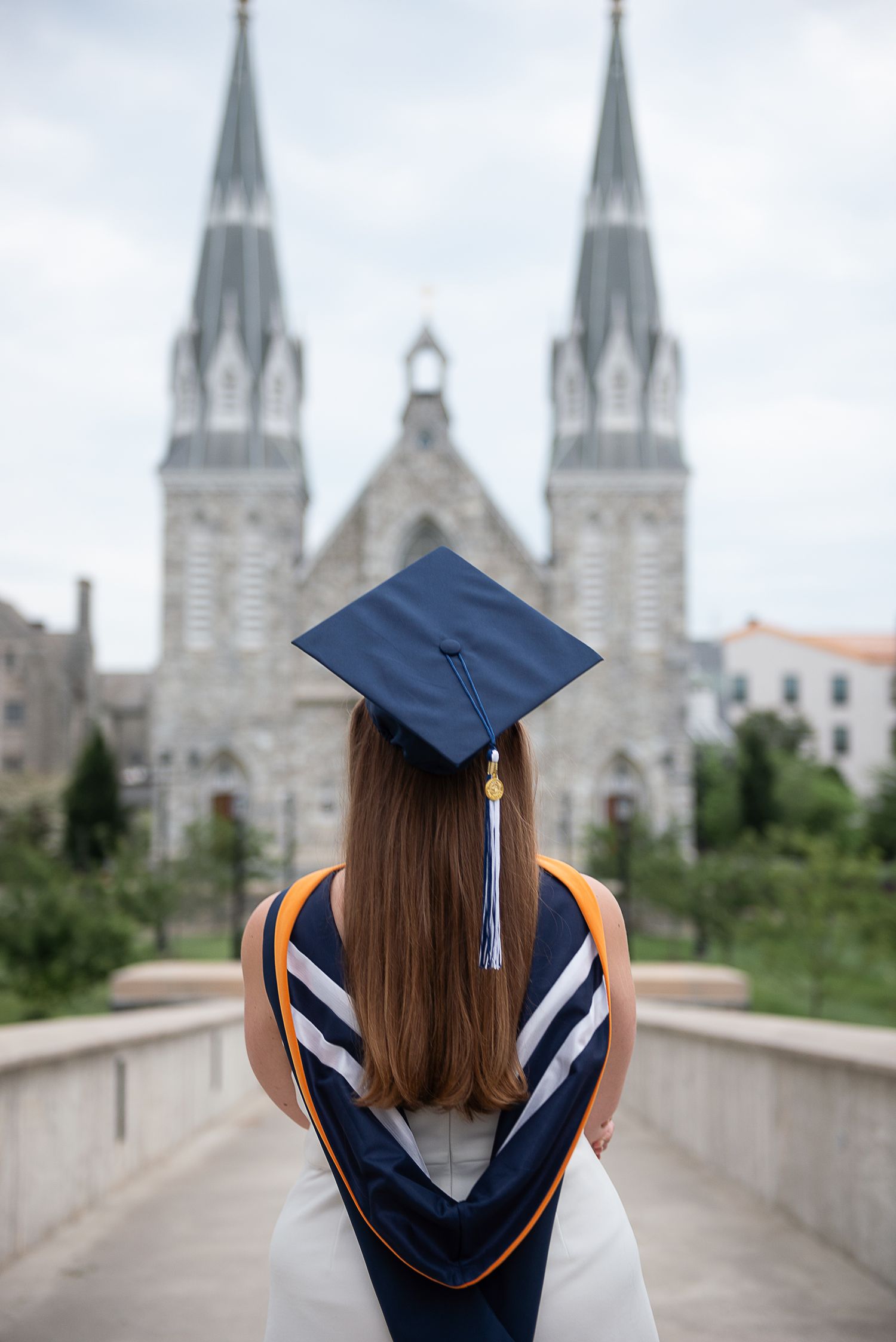A graduation cap and gown silhouetted against gothic cathedral spires on a cloudy day at Villanova University.