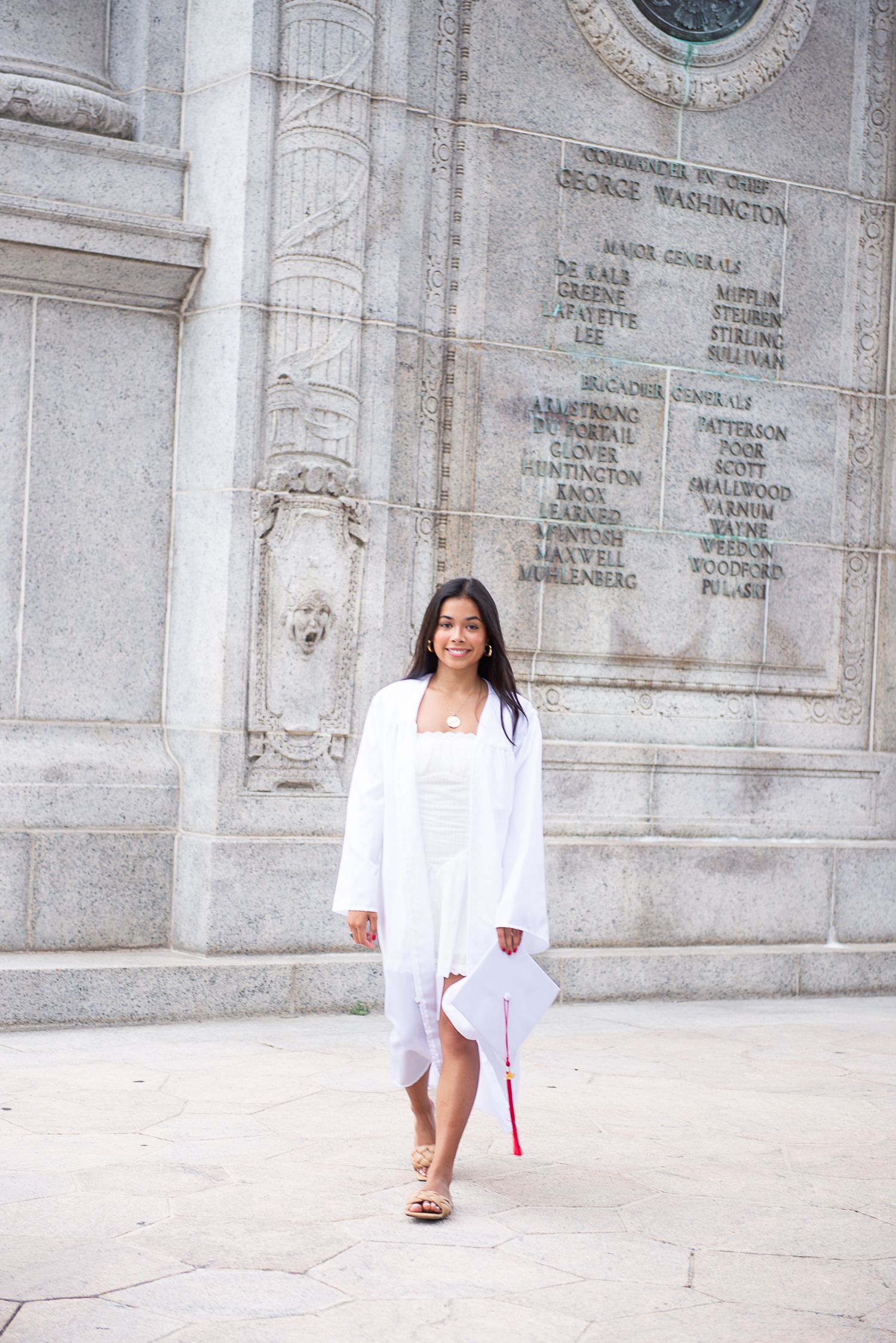 A white graduation ensemble stands out against ornate stone architecture of a historic building at Valley Forge National Historic Park.