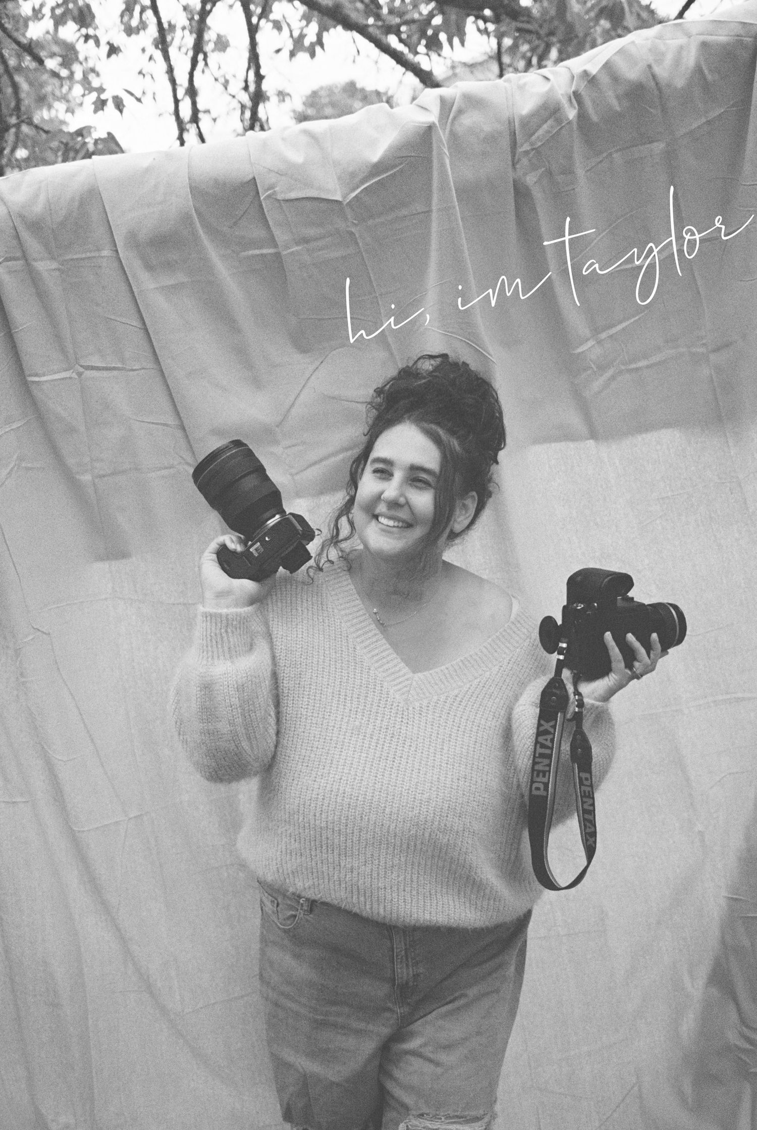 Black and white photo of a photographer holding two cameras against a light colored backdrop with handwritten text.