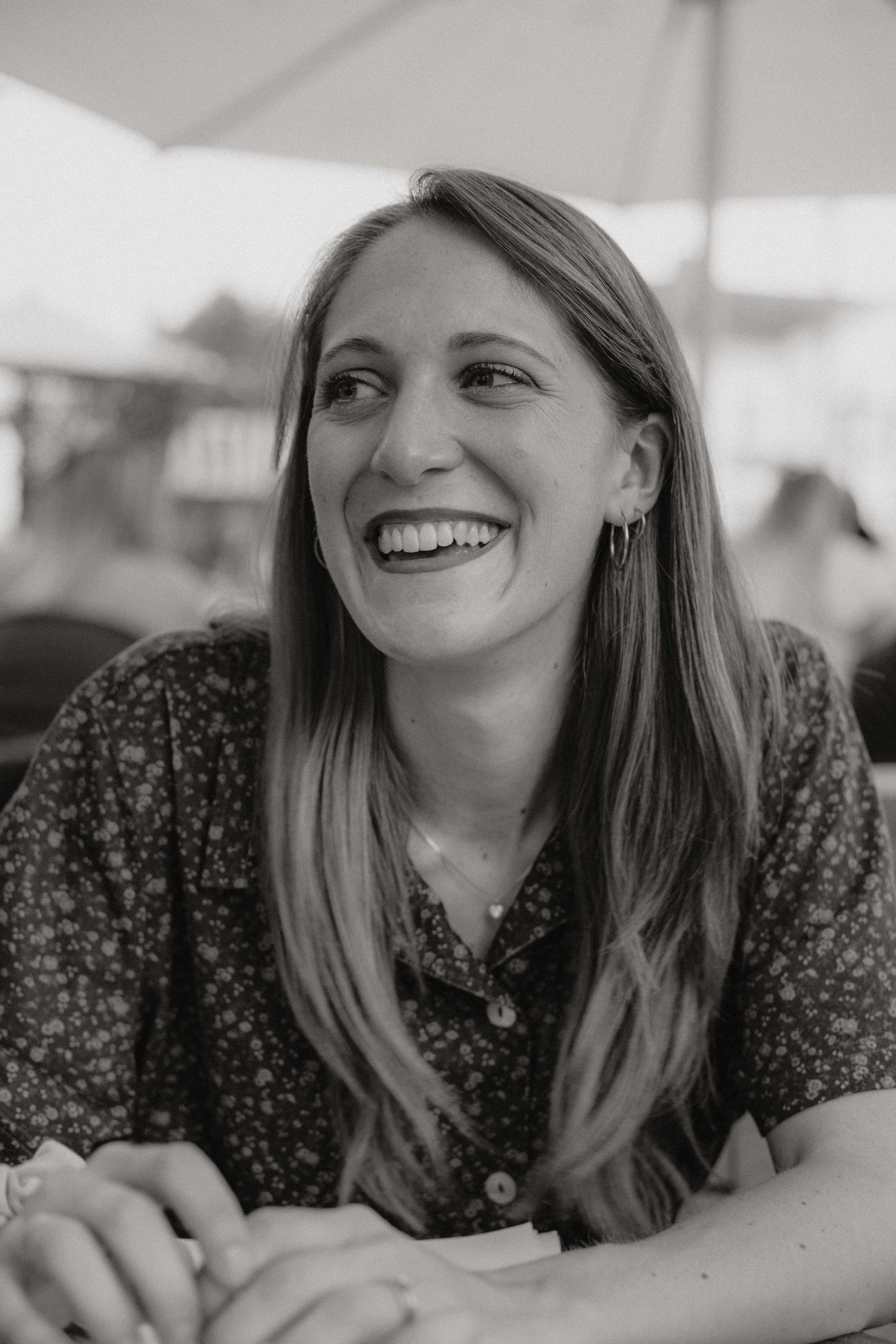A casual portrait of someone laughing while resting on their arms in black and white.