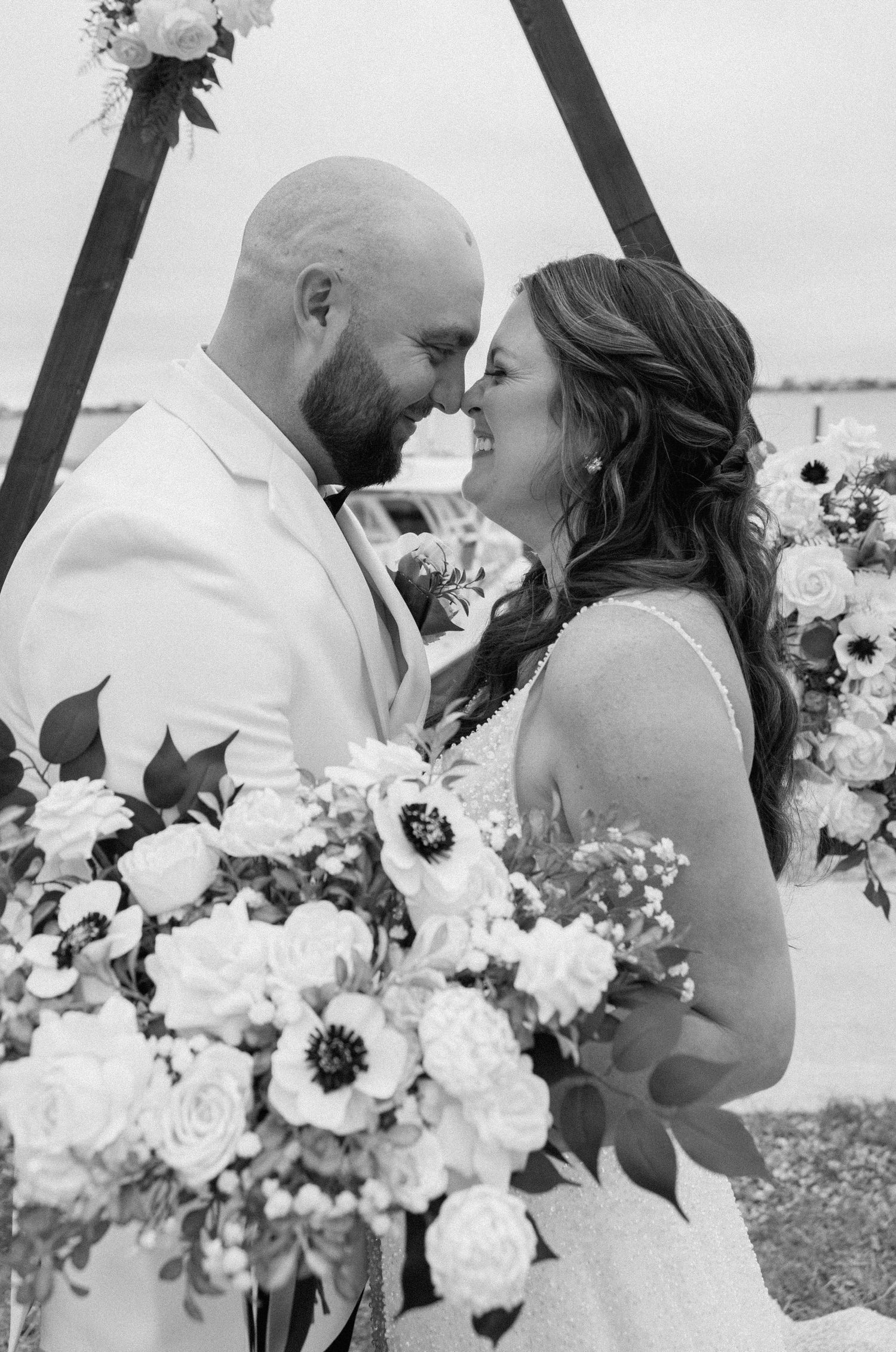 Black and white wedding portrait of a bride and groom embracing and holding a bouquet.