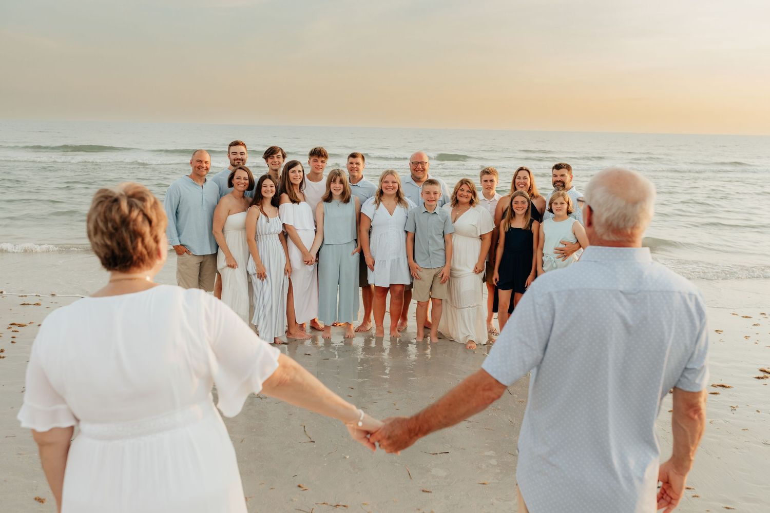Large group gathered together on the beach during a sunset family photography session.