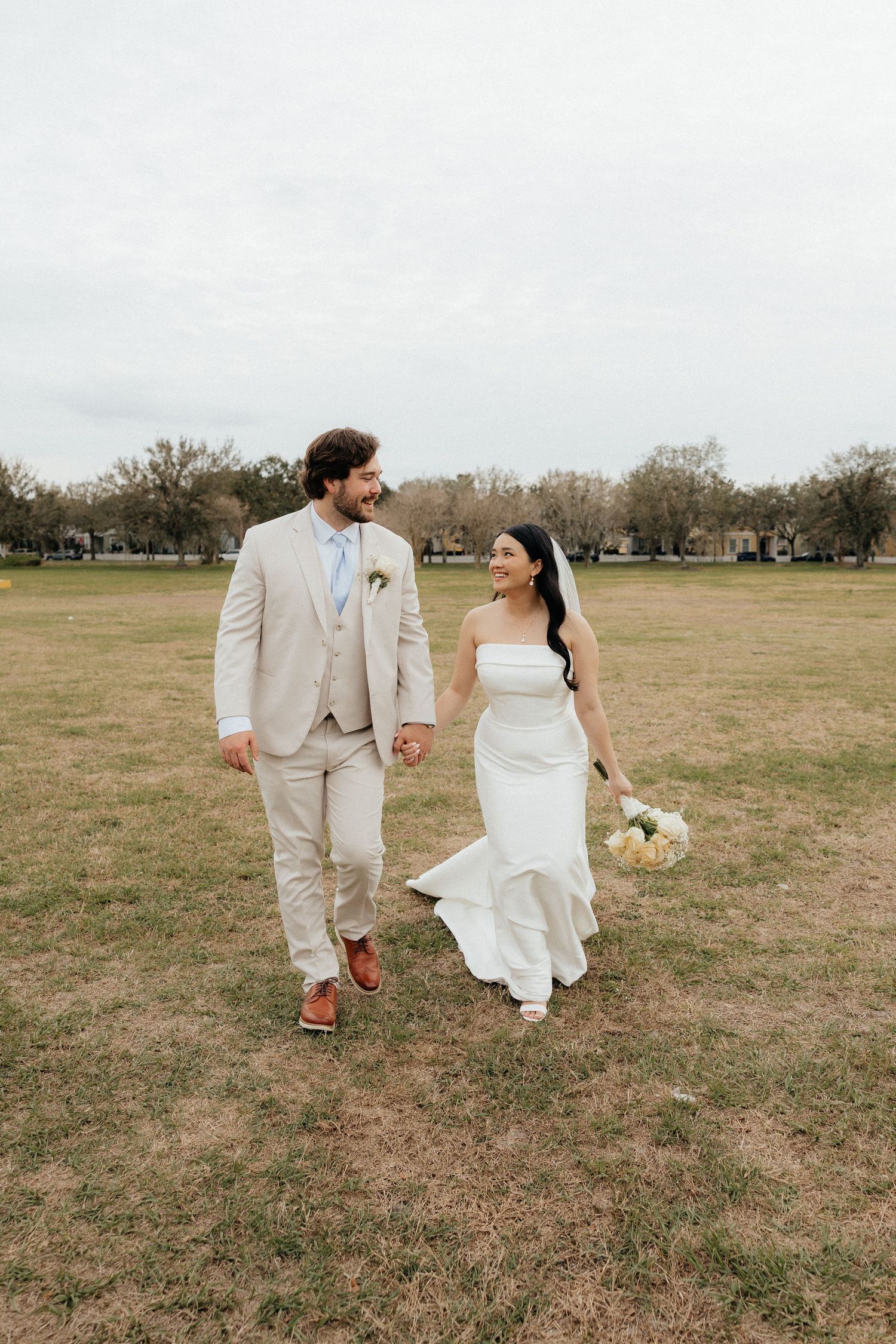Couple walking hand in hand through an open field during an outdoor couples session.