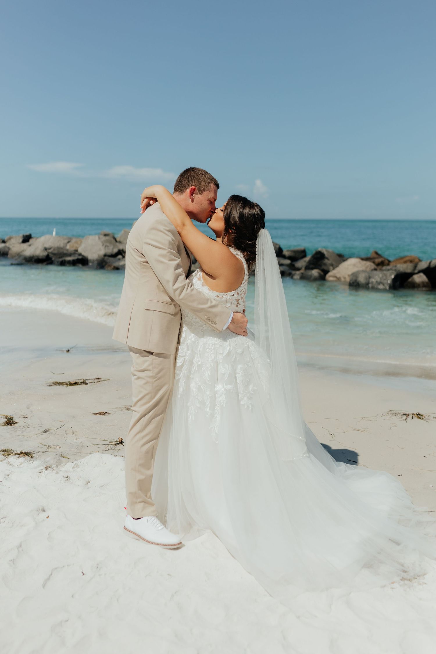 Bride and groom embracing on the beach during a wedding portrait session.