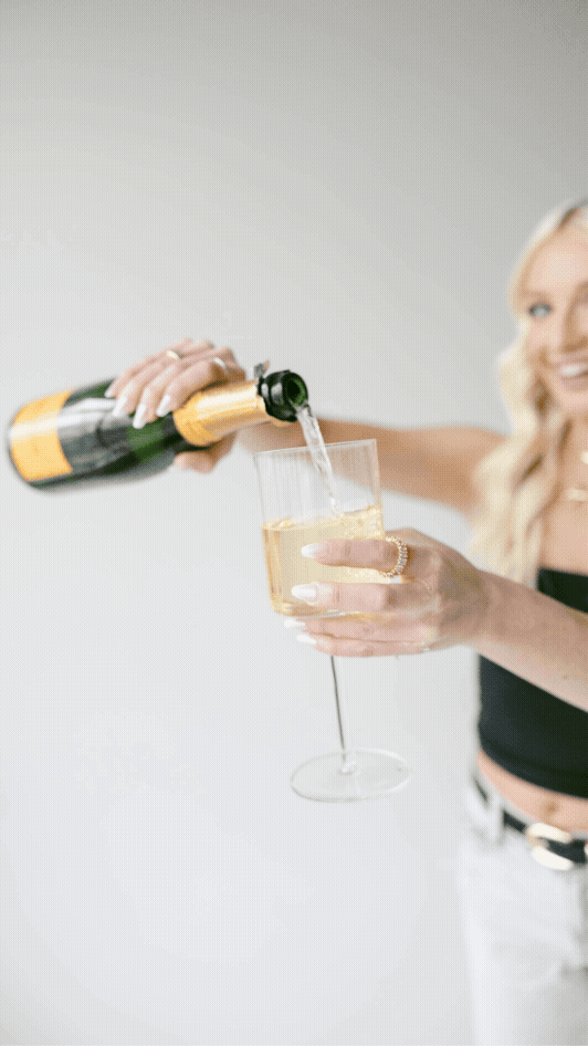 Hands pouring champagne into elegant glasses against a white background.