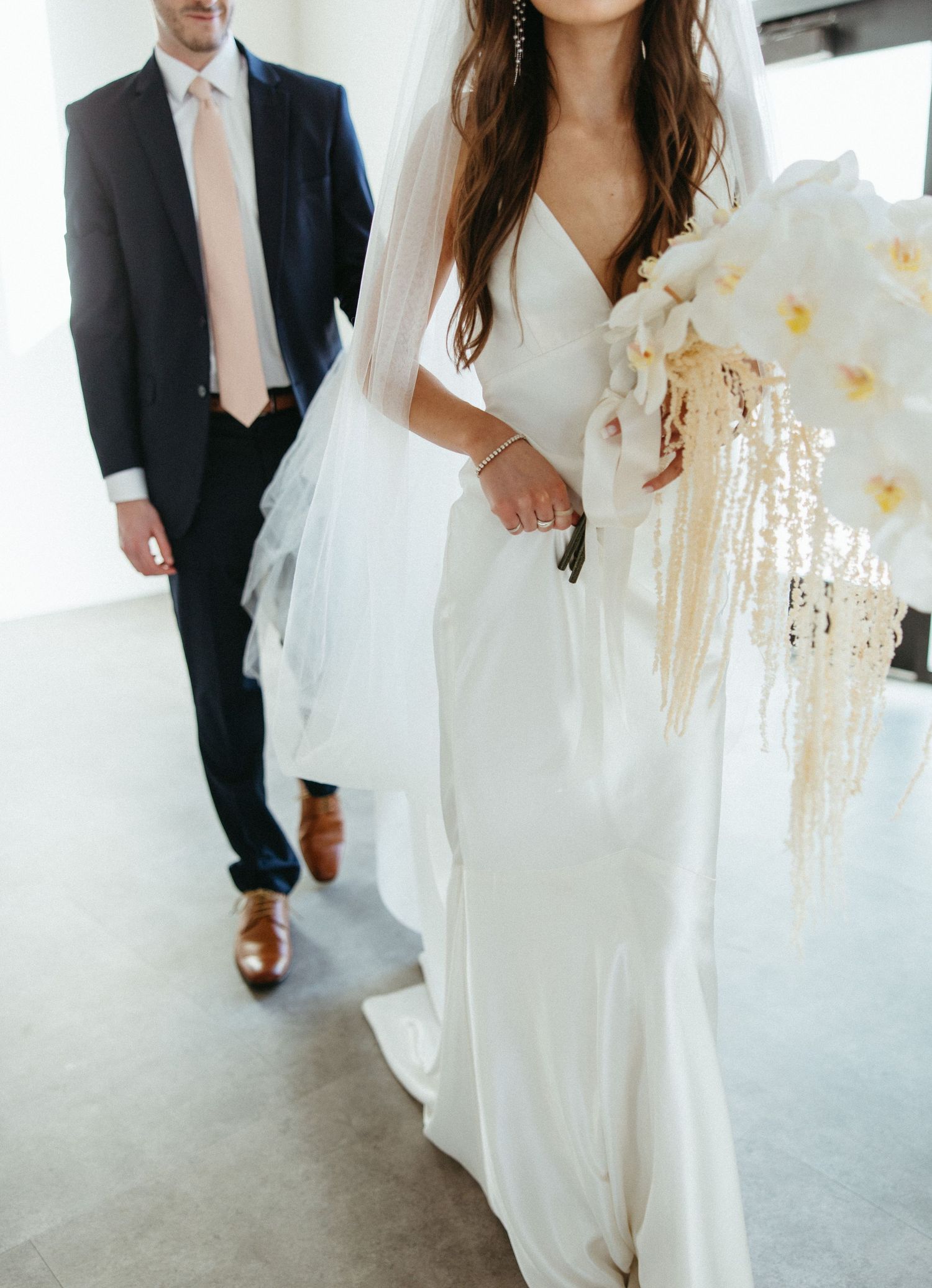 Elegant wedding attire detail showing white dress and dark suit with brown leather shoes.
