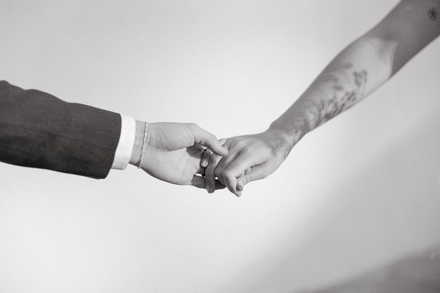 Black and white photo of hands exchanging wedding rings during ceremony.