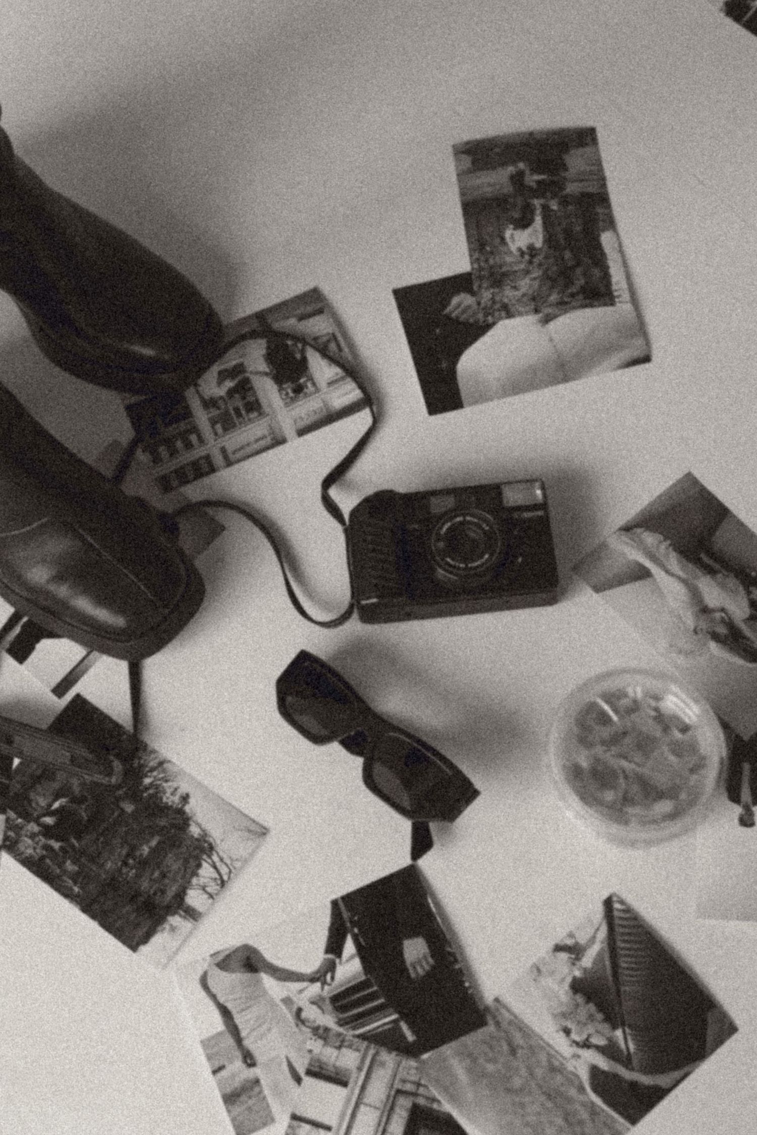 Black and white artistic composition of scattered photographs and objects.