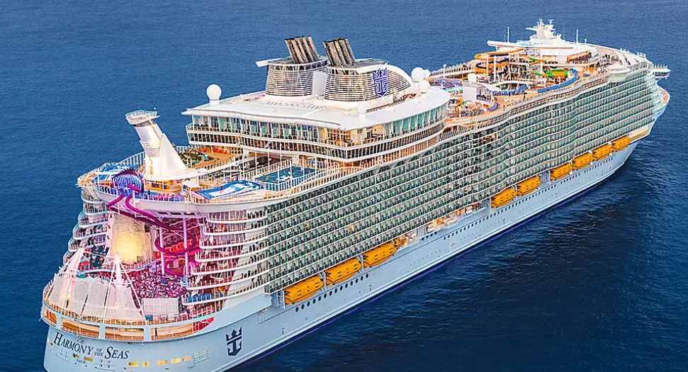 Aerial view of multiple Royal Caribbean cruise ships docked in a row against bright blue ocean waters.