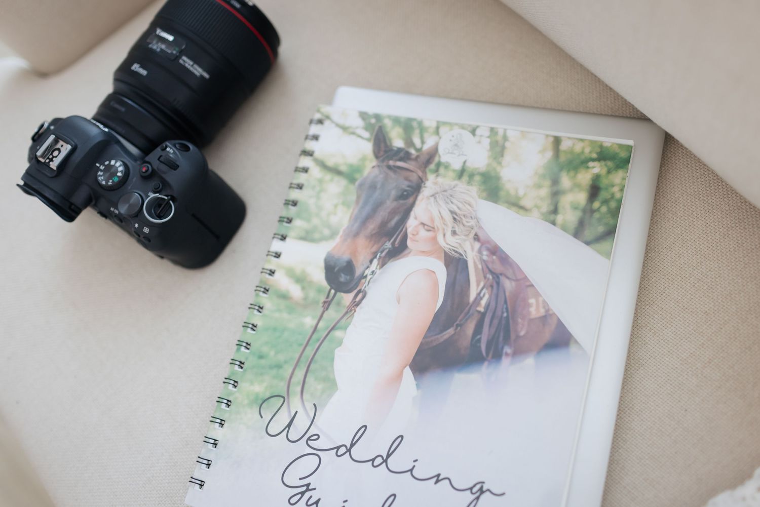 Wedding planning notebook with camera and horse photo on beige surface.