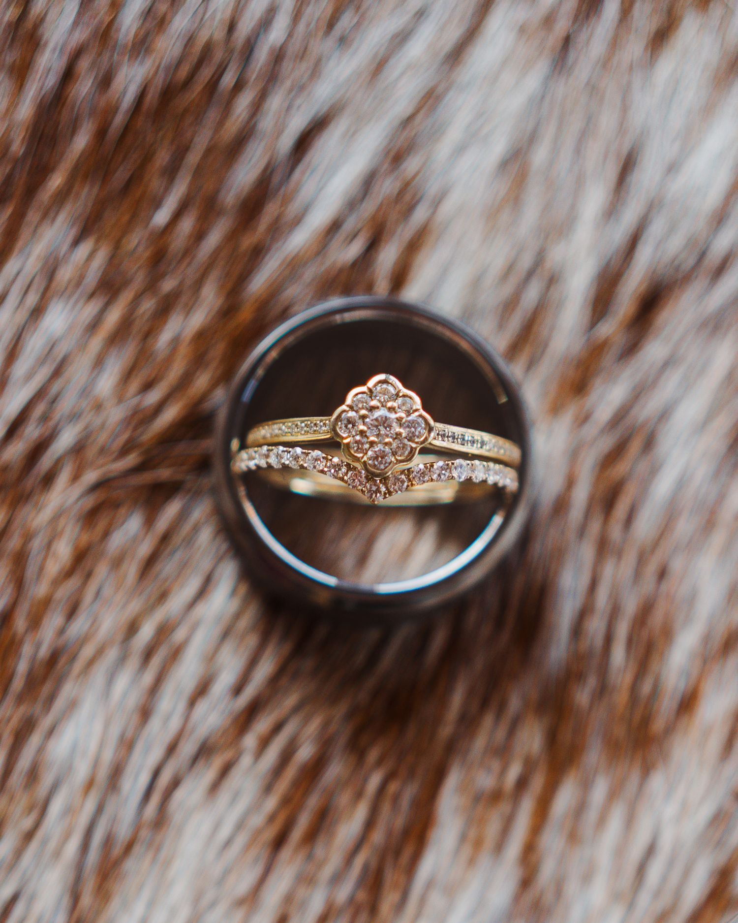 Close-up of an elegant gold floral diamond engagement ring set displayed in a dark ring box.