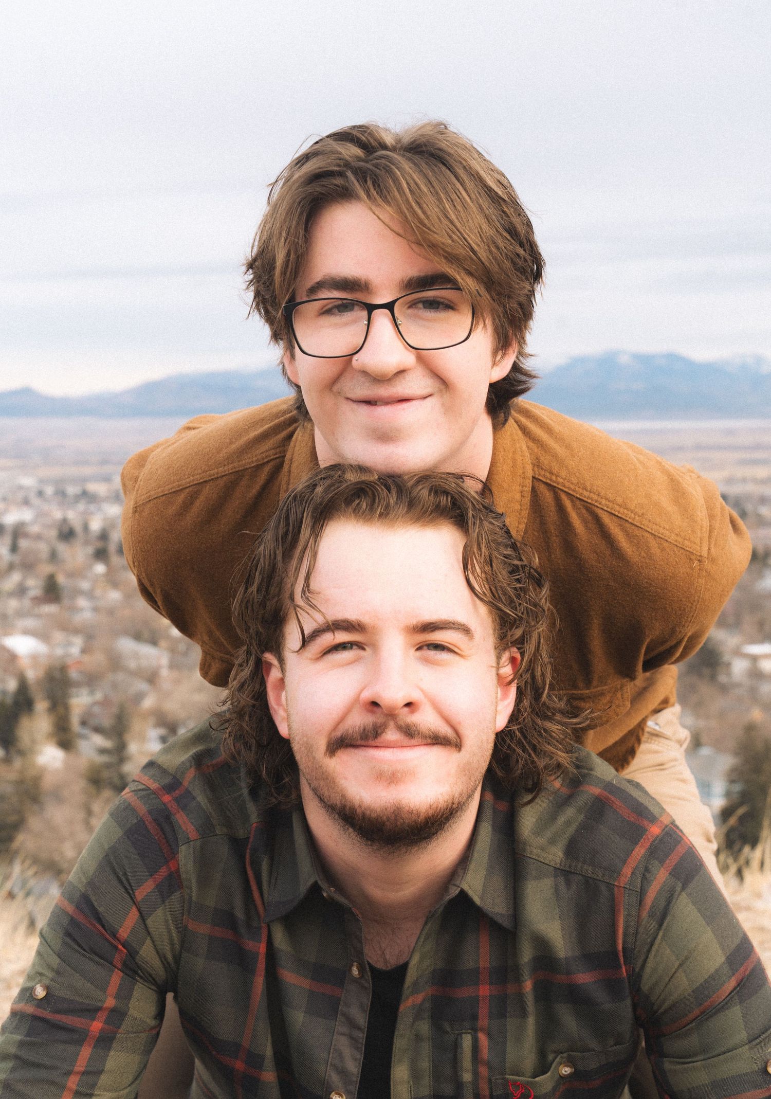 Brothers posing playfully stacked together with a scenic mountain town backdrop. Family and holiday photos in Helena Montana.