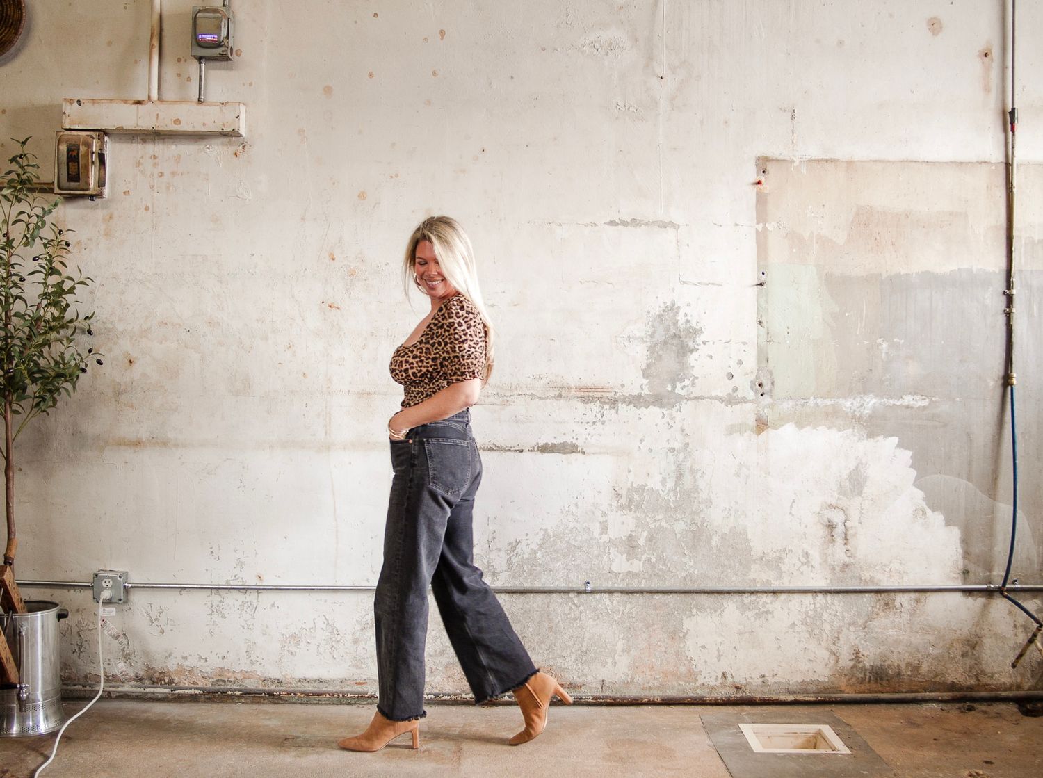 Personal branding photography in Stanly County featuring Lauren of Elle Luna Interiors Design, walking through a bright industrial studio.