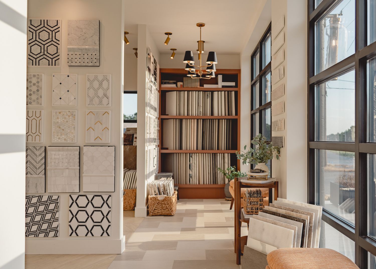 Modern interior space with tall record shelf, geometric wall tiles, and large windows letting in natural light.