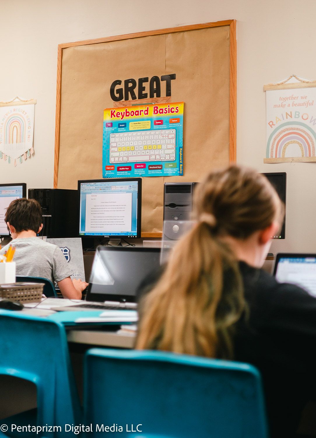Computer lab workstations with monitors lined up against beige walls displaying educational materials.