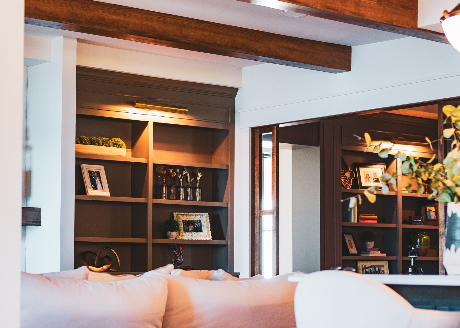 Built-in wooden shelving with warm lighting displays books and decor in a cozy living room corner.