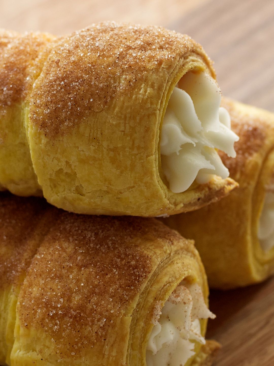 Freshly baked cream horns dusted with sugar show layers of flaky pastry filled with smooth white cream.