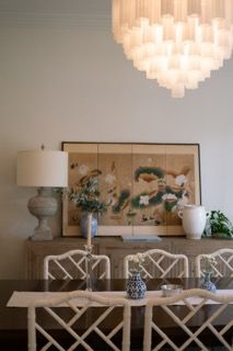 A series of modern dining chairs with geometric fretwork backs arranged in a row along a beige wall.