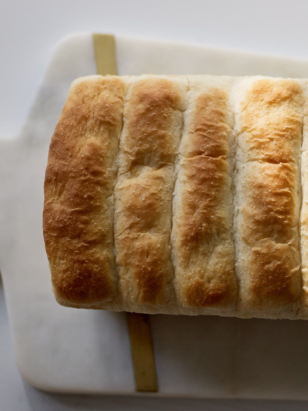 Close-up sequence of a sliced baguette on a white surface showing its golden crust and fluffy interior.