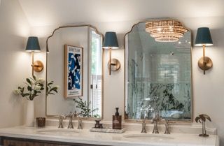 Panoramic view of a luxurious modern bathroom with crystal chandelier, marble countertops, and elegant wall sconces.