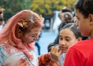A group of people enjoying an outdoor event with someone's pink hair flowing in the breeze.
